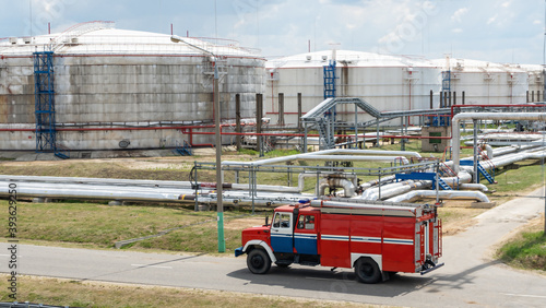 Fire truck in industrial plant. A large red fire rescue vehicle in the chemistry refinary plant on petroleleum tanks background. Fire safety concept. photo