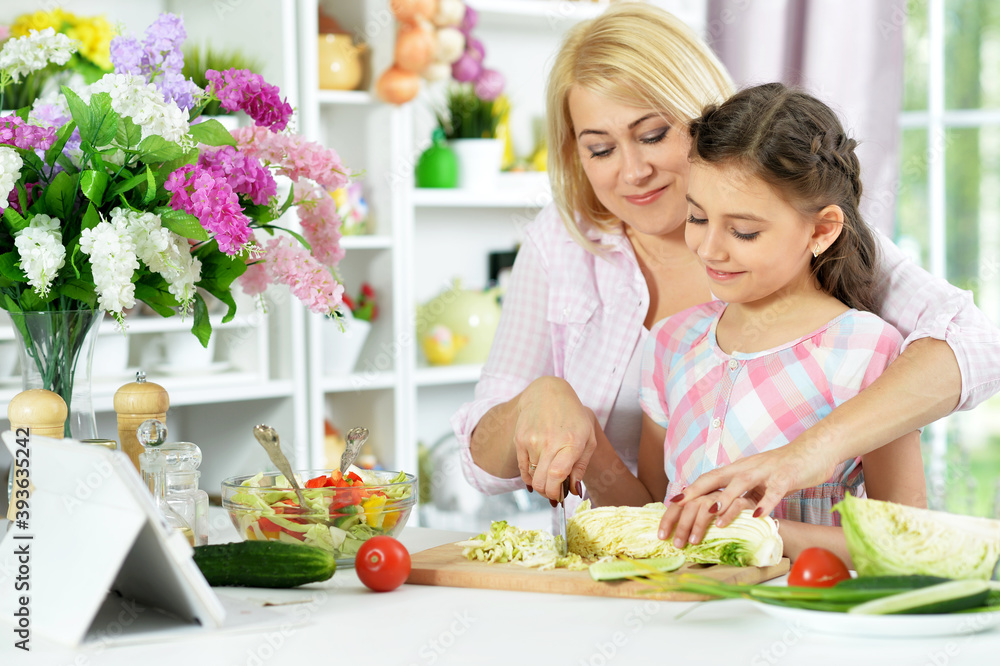 Cute little girl with her mother cooking together Cute little girl with her mother cooking together