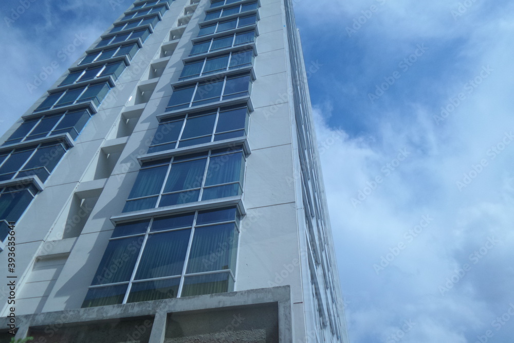 Edge of modern apartment tower with glassy design and cloudy sky Edge of modern apartment tower with glassy design and cloudy sky