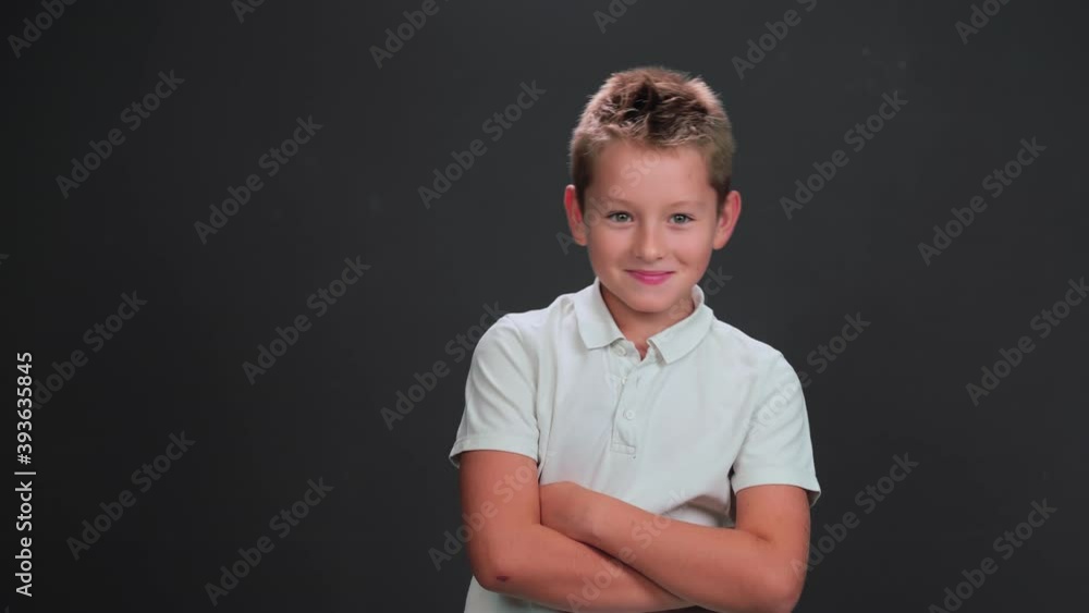 Caucasian 10 years boy looks side ways in surprise or terrified. Child with his arms folded poses on black background. Surprise or scare concept. Caucasian 10 years boy looks side ways in surprise or terrified. Child with his arms folded poses on black background. Surprise or scare concept.
