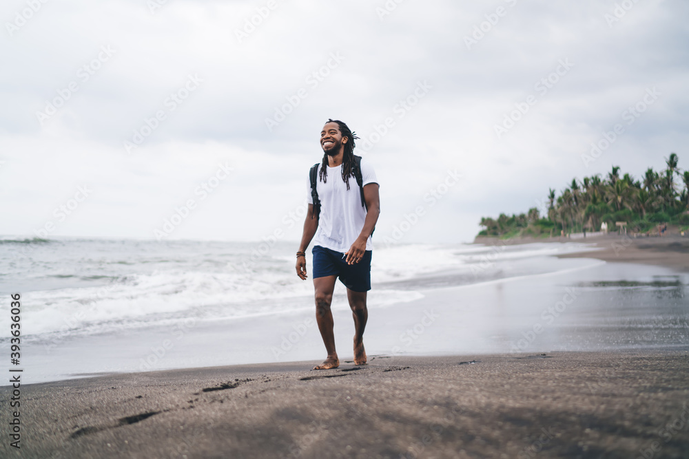 Content black man strolling on coast