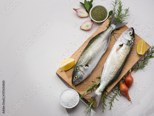 Raw fresh bluefish on cutting board. Background is white marble photo