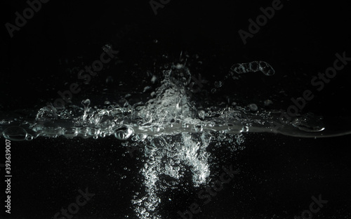 Water splashing as it's poured into aquarium tank, black background