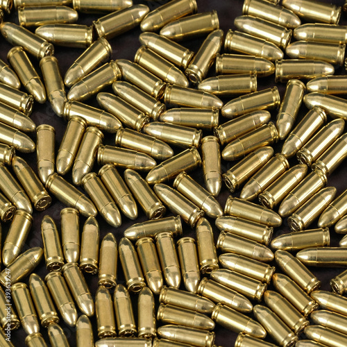 Slika na platnu Many brass gun bullets on black table closeup view from above