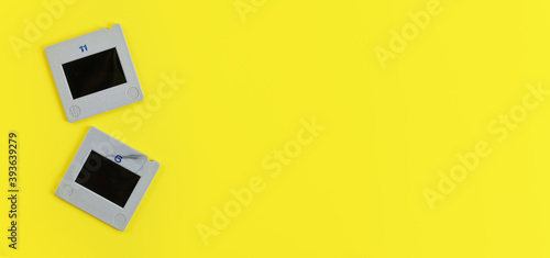 Two diapositive photo slides on yellow table, view from above, space for text right side, retro photography concept