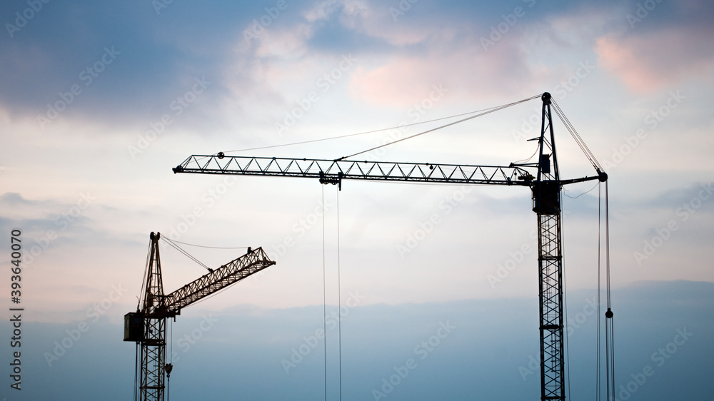Construction banner. Cranes in front of sunset sky. Building concept. Copy space