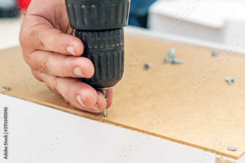 Assembly of furniture, the carpenter screws a self-tapping screw into a drawer with a screwdriver