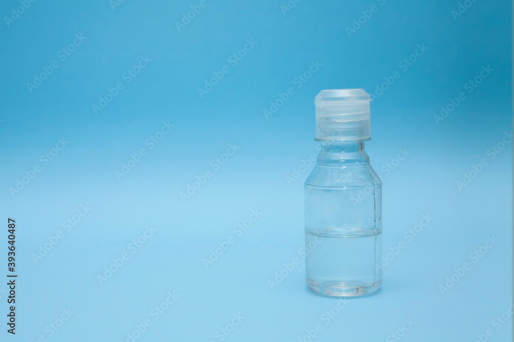 Bottle with transparent liquid on a blue background. Sanitizer. Hygiene. Bottle with transparent liquid on a blue background. Sanitizer. Hygiene.