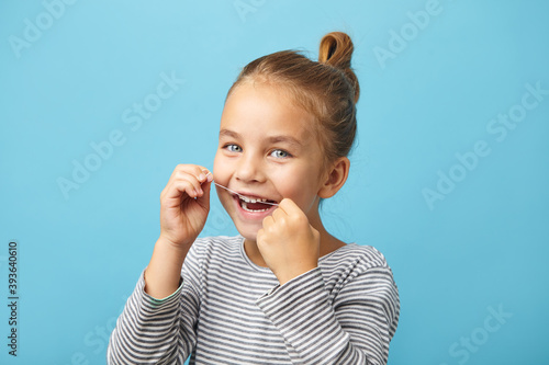 Dental flush, caucasian child girl using flossing teeth and smiling photo