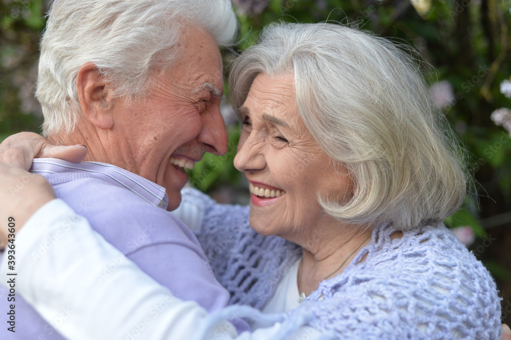 Beautiful senior couple hugging by lilacs in the park