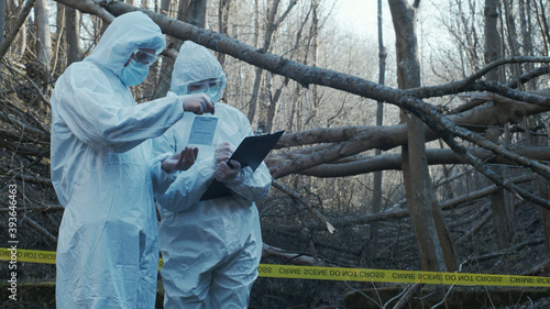 Detectives are collecting evidence in a crime scene. Forensic specialists are making expertise. Police investigation in a forest.