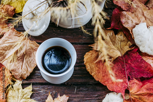 Tasse de café expresso en grès blanc et arrière plan avec des feuilles d'automne et un bouquet de fleurs séchées aux couleurs brun jaune d'automne
