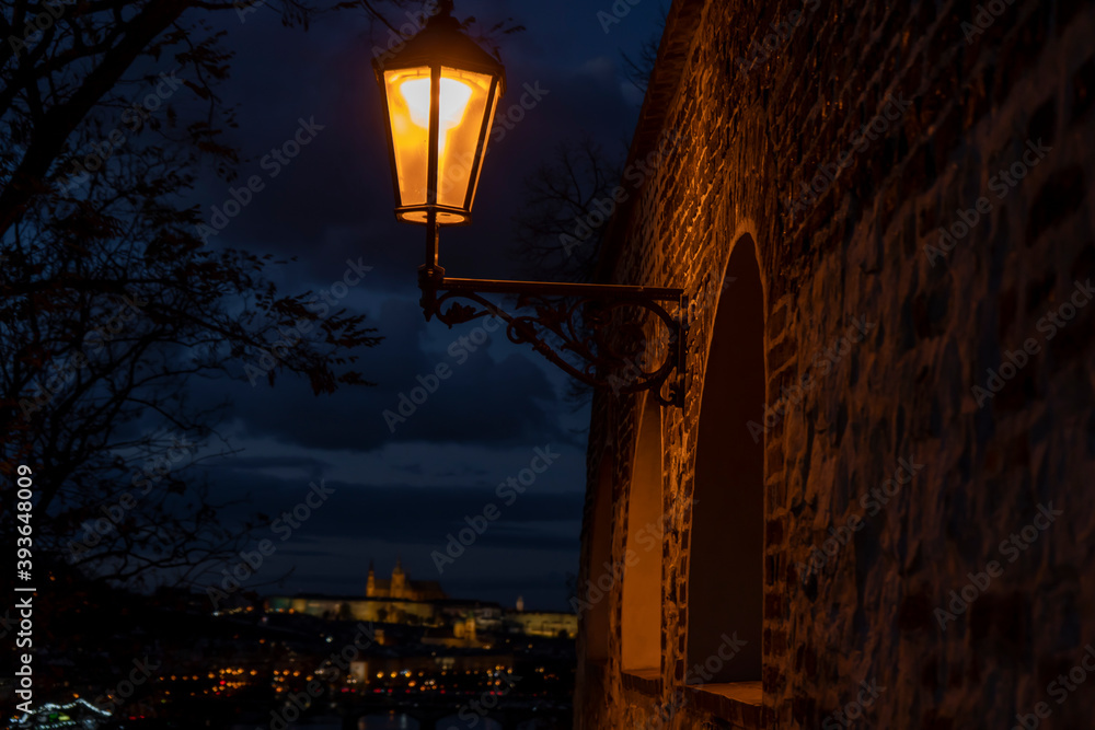 
light from street lights and the old stone walls of the fortress from the 15th century and paving stones on the ground for pedestrians at night in the center of Prague in the Czech Republic in autumn