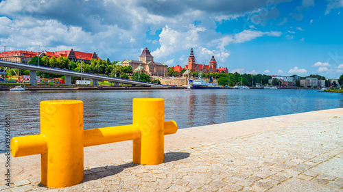 Large, defocused yellow mooring cleat on pier with view on boats, National Museum, Chrobry Shafts and old passport office building in Szczecin, Poland photo