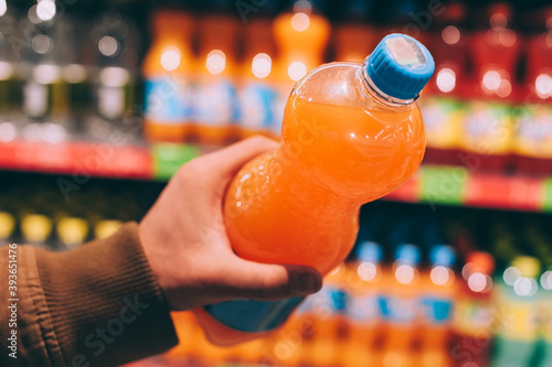 A man in a supermarket holds a bottle of sweet drink in his hands. photo