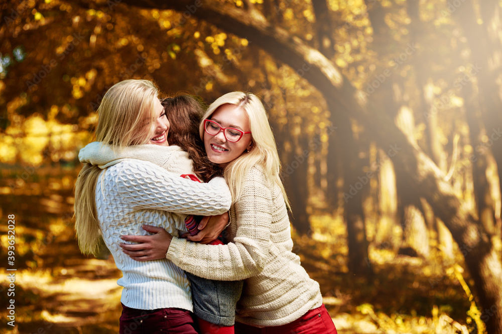 Fototapeta premium Three happy lovely sisters hugging in autumn park