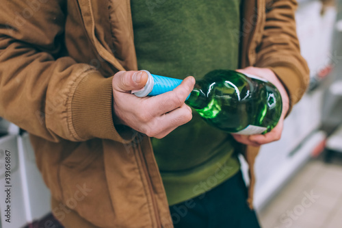 A shopper in a supermarket holds wine in his hands. Concept on the topic of selection of goods.