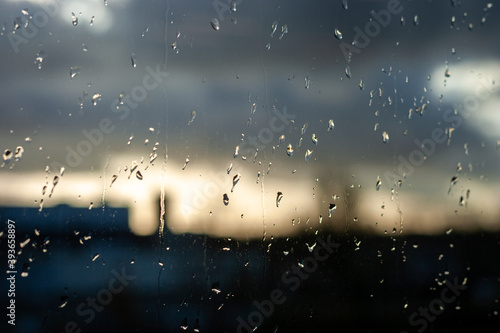 Raindrops on the glass of a window, blurred cloudy sky in the background