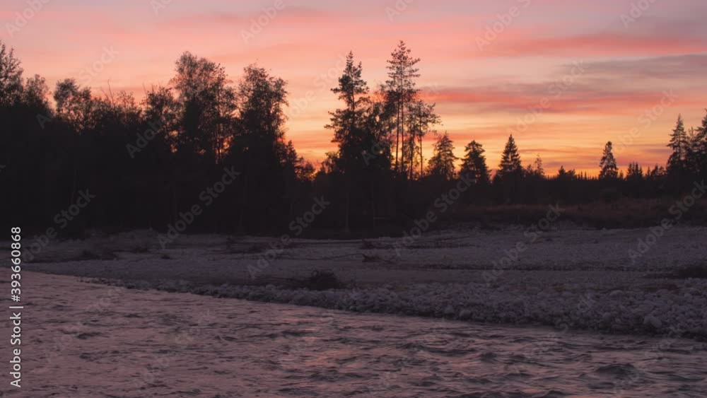 Evening scene at the river, silhouettes of trees at the rocky shore with sunset coloured sky background Evening scene at the river, silhouettes of trees at the rocky shore with sunset coloured sky background