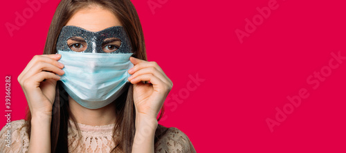 Banner. Girl in a carnival and medical mask, on red background with blank space.