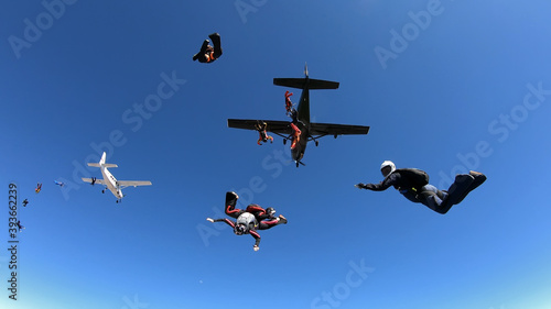 Skydivers jump out of tow airplanes with blue skies