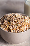Rye flakes in a round wooden bowl with glass of milk on a stone background. Healthy cereal flakes in a ceramic bowl and milk close-up.