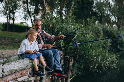 boy fishing on the lake with his grandfather