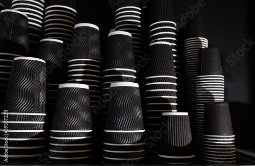 Disposable paper cups in coffee shop. Background of folded black paper cups. Blurred image, selective focus