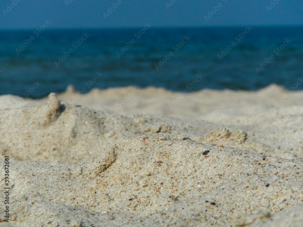 A view of the sand on the beach with the sea blurred in the background A view of the sand on the beach with the sea blurred in the background