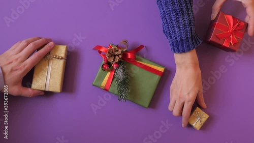 Female and male hands pick gift boxes, presents from the violet background. Little fight for the last gift. Top view. Celebrating Christmas or New Year.  photo