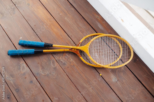 Badminton rackets lie on the wooden veranda © mrkotov