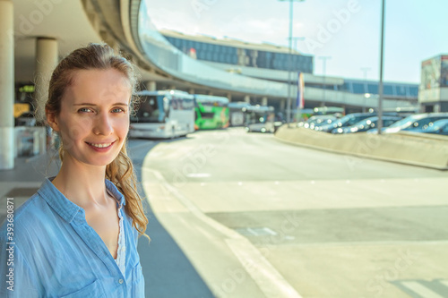 Canvas Print Selfie portrait of a beautiful modern long haired woman standing on background of the airport building and transport stops on a sunny day