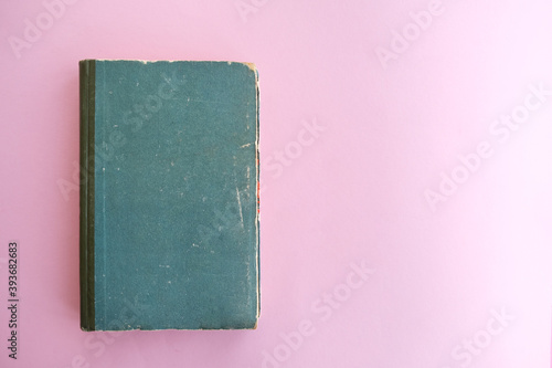 Old book of green color on a pink background.
