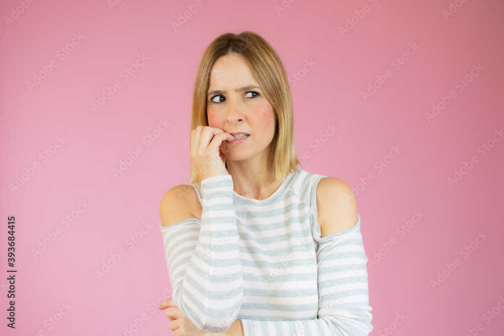 Young beautiful woman wearing casual t-shirt standing over isolated pink background looking stressed and nervous with hands on mouth biting nails. Anxiety problem. Young beautiful woman wearing casual t-shirt standing over isolated pink background looking stressed and nervous with hands on mouth biting nails. Anxiety problem.