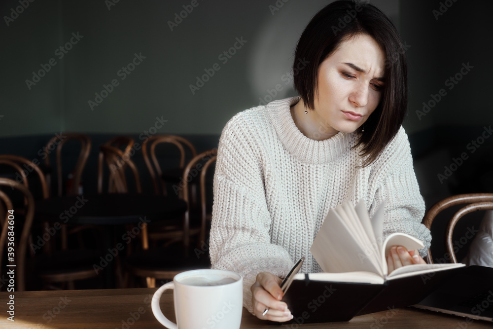 A girl in a cafe makes notes in a notebook A girl in a cafe makes notes in a notebook