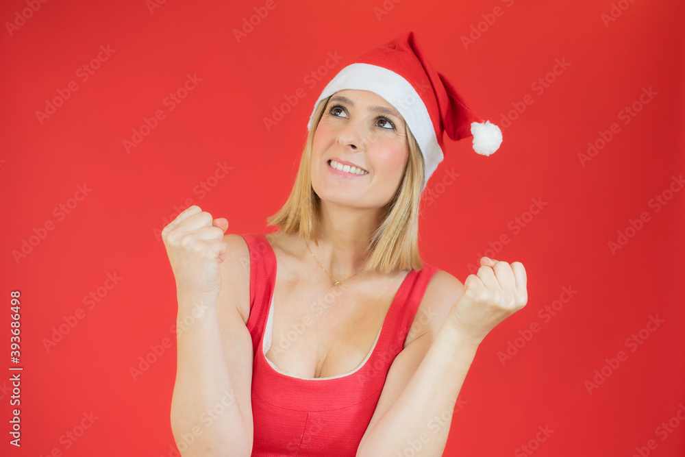 Young blonde woman wearing christmas hat over isolated background very happy and excited doing winner gesture with arms raised, smiling and screaming for success. Celebration concept. Young blonde woman wearing christmas hat over isolated background very happy and excited doing winner gesture with arms raised, smiling and screaming for success. Celebration concept.