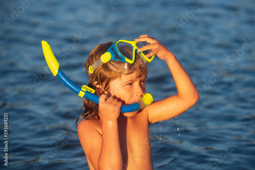 Kid boy snorkeling on the beach on blue sea in summer. Blue ocean with wawes. Child boy swimming in sea.