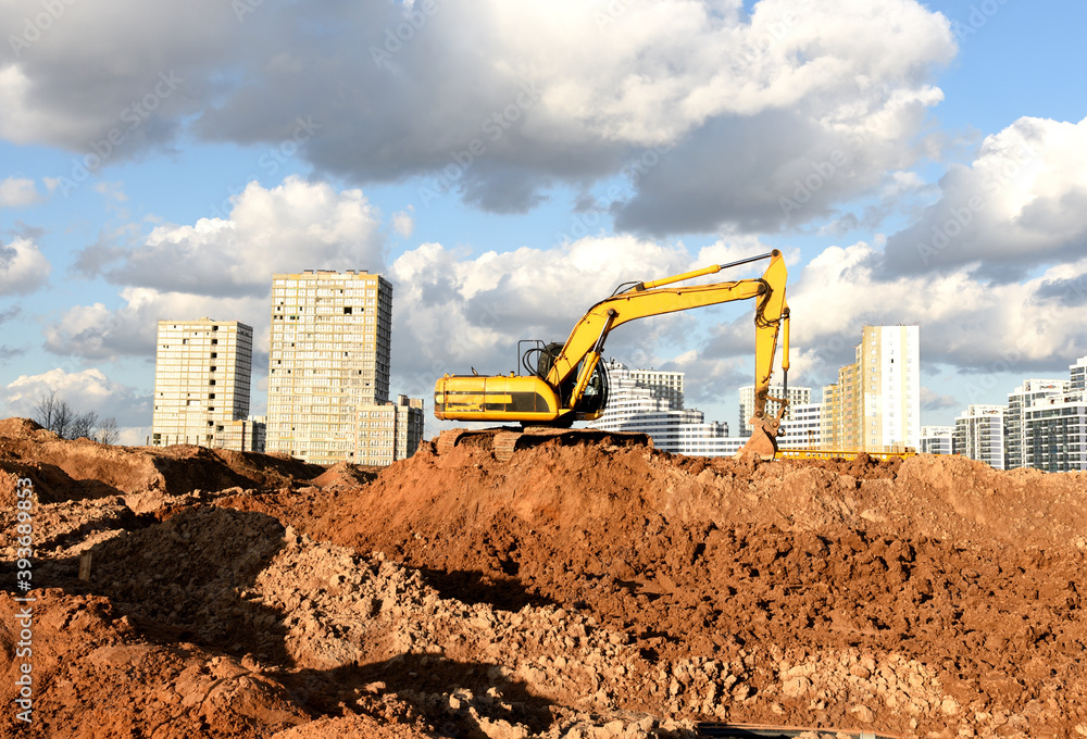 Excavator during earthmoving at construction site. Backhoe dig ground for the construction of foundation and laying sewer pipes district heating. Earth-moving heavy equipment on road works Excavator during earthmoving at construction site. Backhoe dig ground for the construction of foundation and laying sewer pipes district heating. Earth-moving heavy equipment on road works