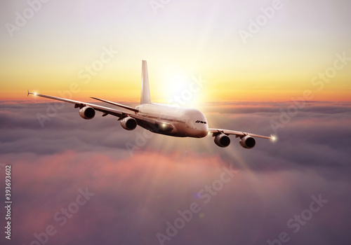 Commercial airplane flying above clouds in dramatic sunset light.
