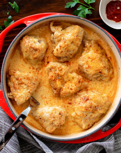 Quadro su tela Poulet Gaston Gerard  served in a red cast iron dish sitting on dark wooden background- It is a traditional dish from the French city of Dijon