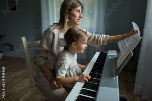 Mom and daughter play the synthesizer while at home.