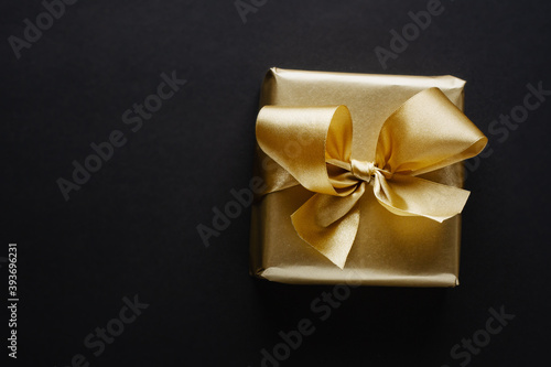 Golden box with golden ribbon on dark