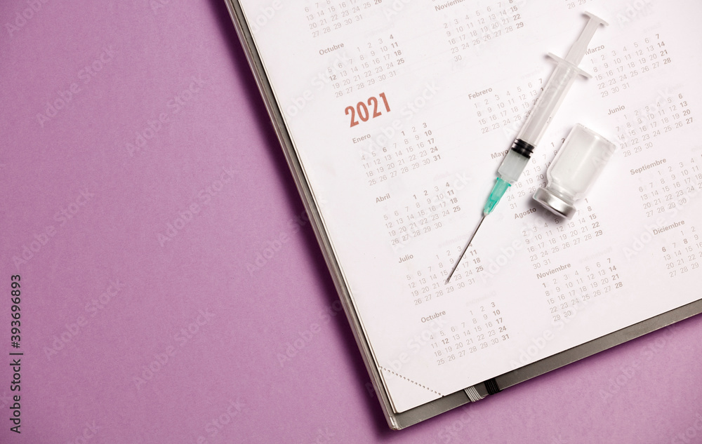syringe and vaccine with calendar 2021, lilac background syringe and vaccine with calendar 2021, lilac background
