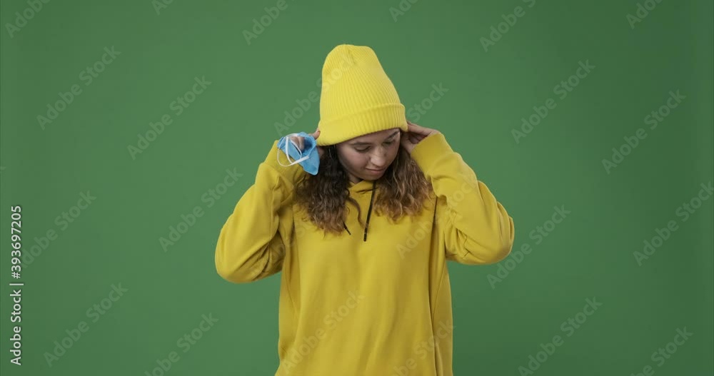 Woman inhaling fresh air on removing protective face mask over green background Woman inhaling fresh air on removing protective face mask over green background