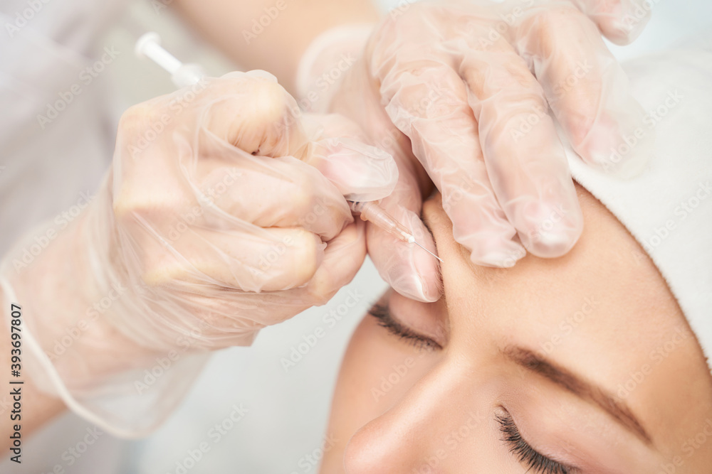 Forehead injection at spa salon. Doctor hands. Closeup. High quality. Pretty female patient. Beauty treatment. Healthy skin procedure. Young woman face. Light background. Plasmolifting rejuvenation Forehead injection at spa salon. Doctor hands. Closeup. High quality. Pretty female patient. Beauty treatment. Healthy skin procedure. Young woman face. Light background. Plasmolifting rejuvenation