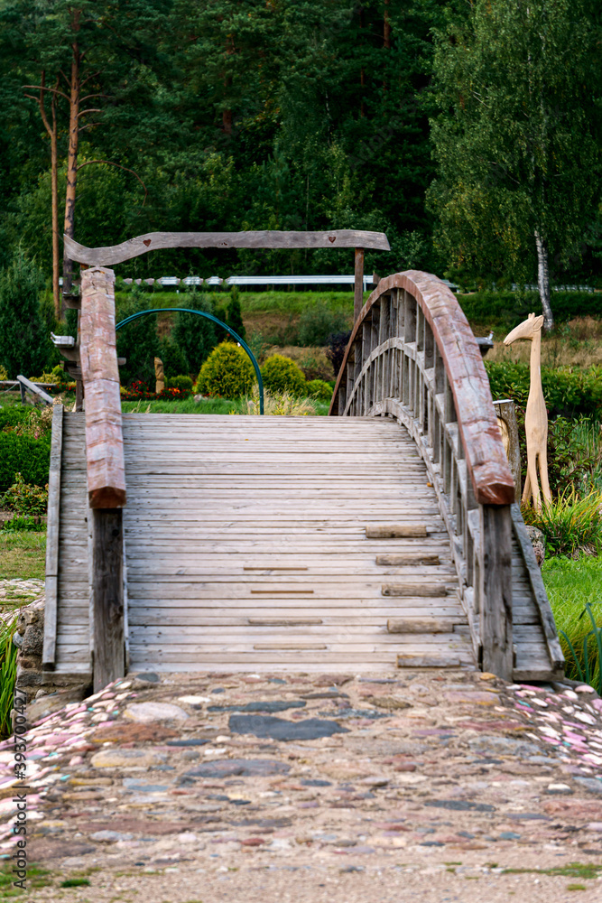 A curved wooden footbridge over a small canal in a summer landscape.