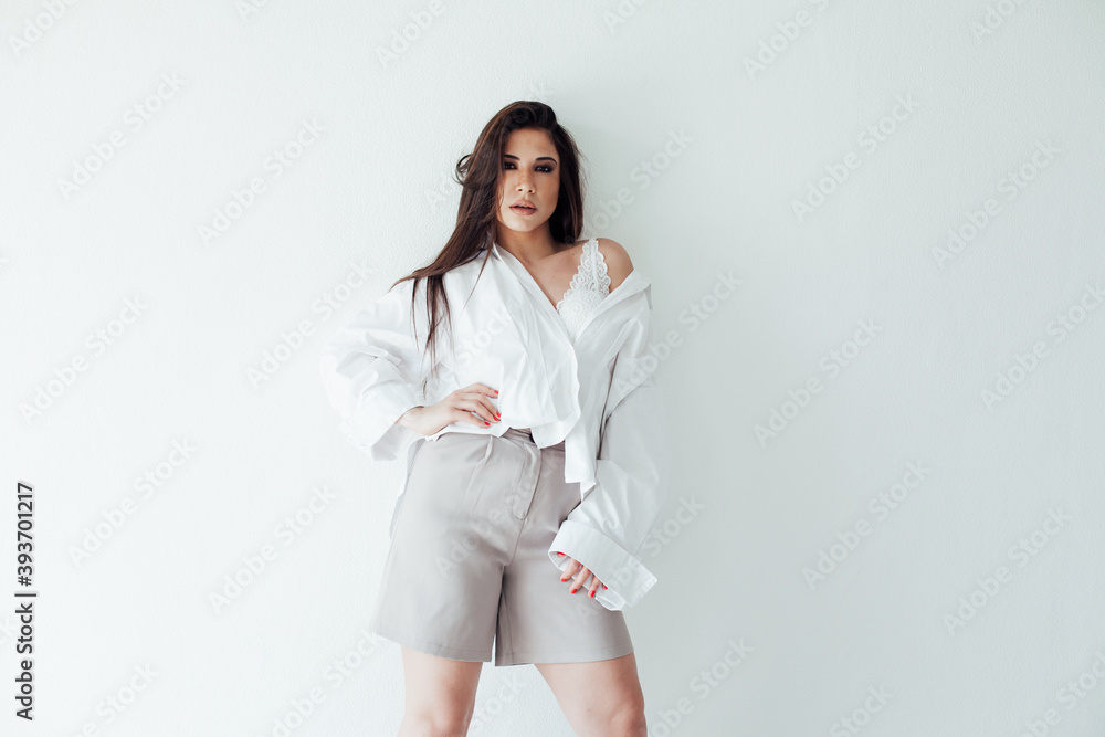 Beautiful fashionable brunette woman in light white men's silk shirt Beautiful fashionable brunette woman in light white men's silk shirt