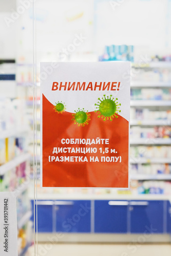 Nizniy Novgorod/Russia-13 07 2020:A poster with warning russian text about safety distance due to coronavirus pandemic of COVID-19 at the entrance to the pharmacy, translation: 