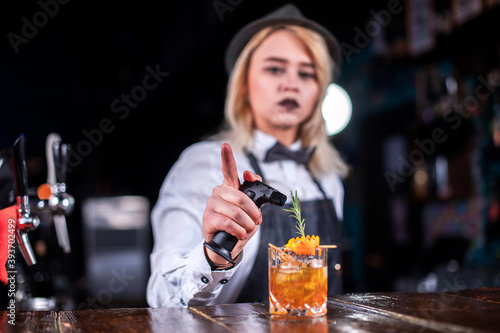 Girl bartender mixes a cocktail in the bar