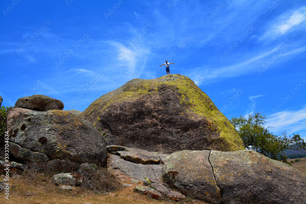 Persona hombre de pie con los brazos extendidos sobre la sima de roca gigante en el parque natural 